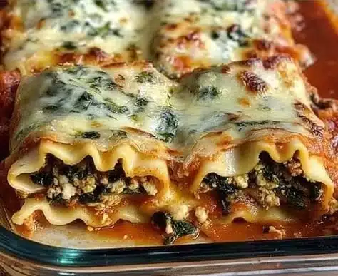 Easy spinach lasagna roll-ups served on a plate with herbs and cheese.