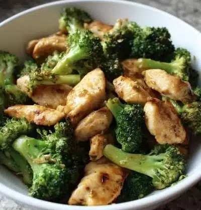 A savory dish of chicken and broccoli served in a bowl garnished with herbs