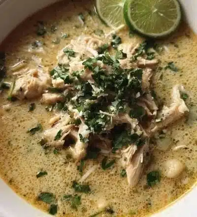 Bowl of creamy white chicken chili garnished with fresh cilantro and lime