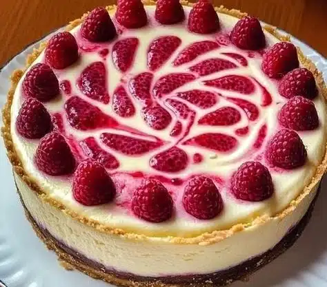 Slice of white chocolate raspberry cheesecake on a plate with fresh raspberries